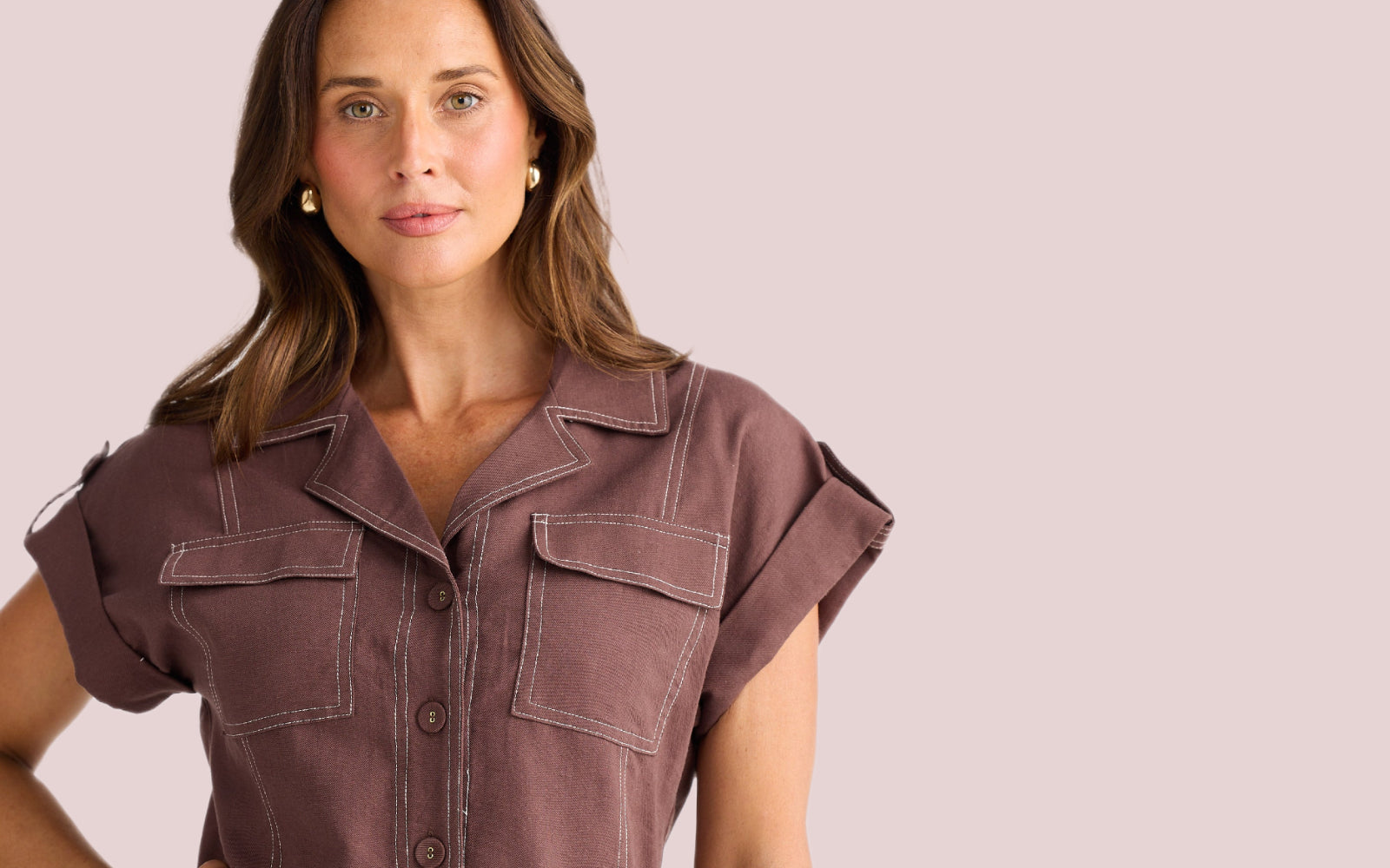 Woman wearing a brown short-sleeve shirt from Brave + Tue clothing pink background